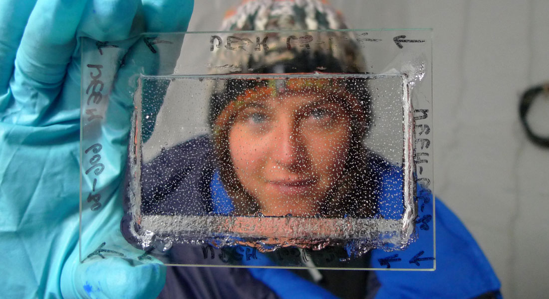 Emilie Capron looks through a thin, polished piece of ice 