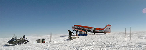  Unloading the Bassler aircraft: Barrels of fuel and drill liquid is rolled down a ramp onto a few sheets of plywood.