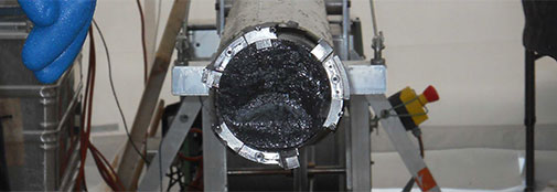The bedrock core sitting in the drill. It is hard to see on the image, but the cutters are damaged to due contact with hard material at the base. The bedrock core sitting in the drill. It is hard to see on the image, but the cutters are damaged to due contact with hard material at the base.